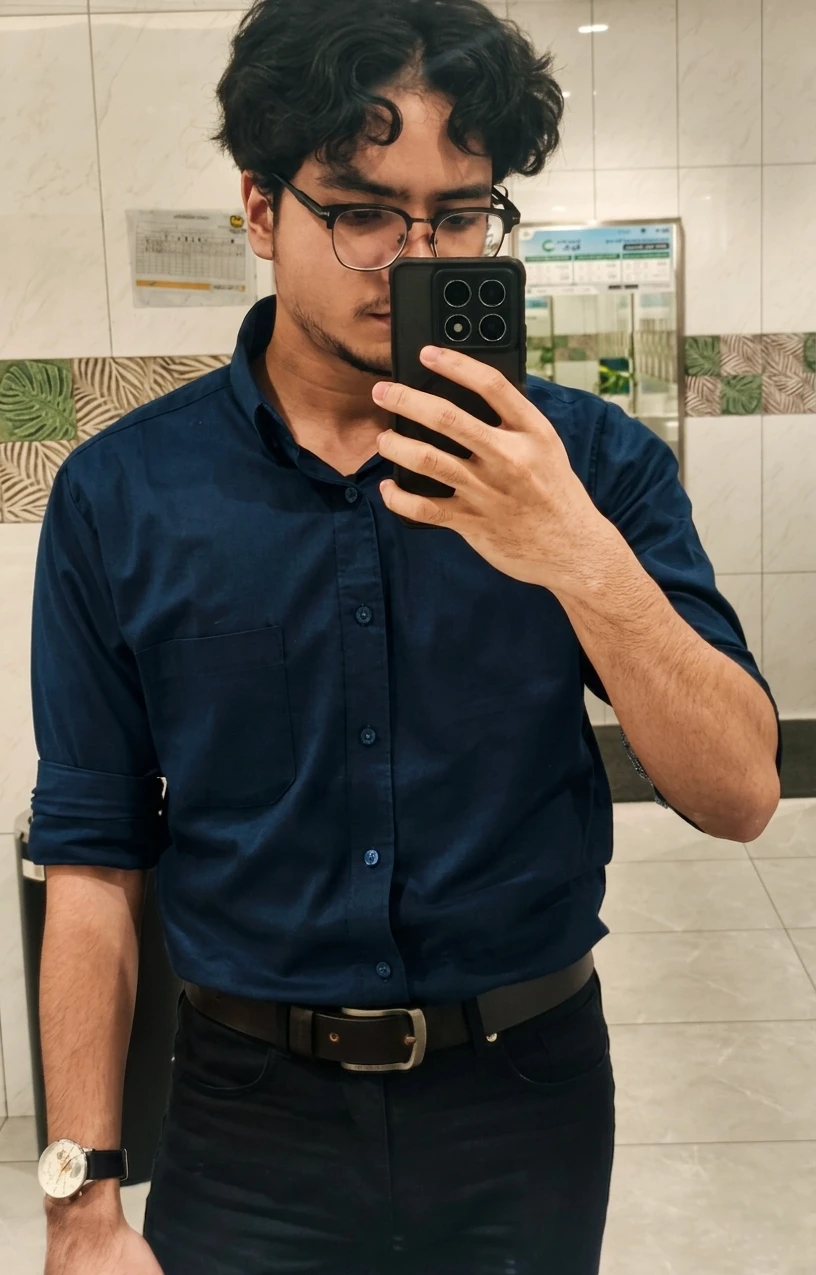 Faqih, mirror selfie in a navy shirt and glasses